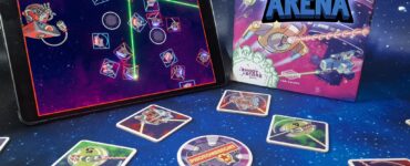 Image of the board game "Light Speed Arena" by T. Jolly and J. Ernest, featuring an iPad displaying the game's digital interface alongside game cards and tokens on a starry background. The scene highlights the interactive gameplay elements and vibrant artwork of the game components.