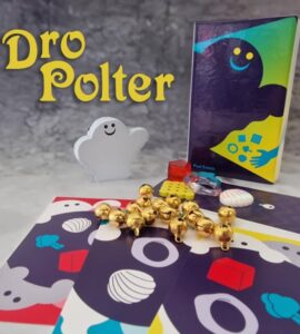 Image of the board game "Dro Polter," featuring a smiling ghost figure, colorful game cards with various designs, and game pieces including gold bells and a red block. The game box is visible, showcasing its vibrant artwork. Ideal for family game nights and fun gatherings.