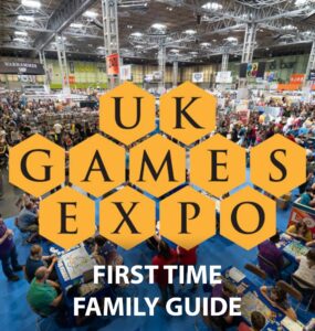 Aerial view of the UK Games Expo showcasing a bustling crowd of attendees engaging with tabletop games and vendors, featuring the event's logo and a "First Time Family Guide" text overlay.