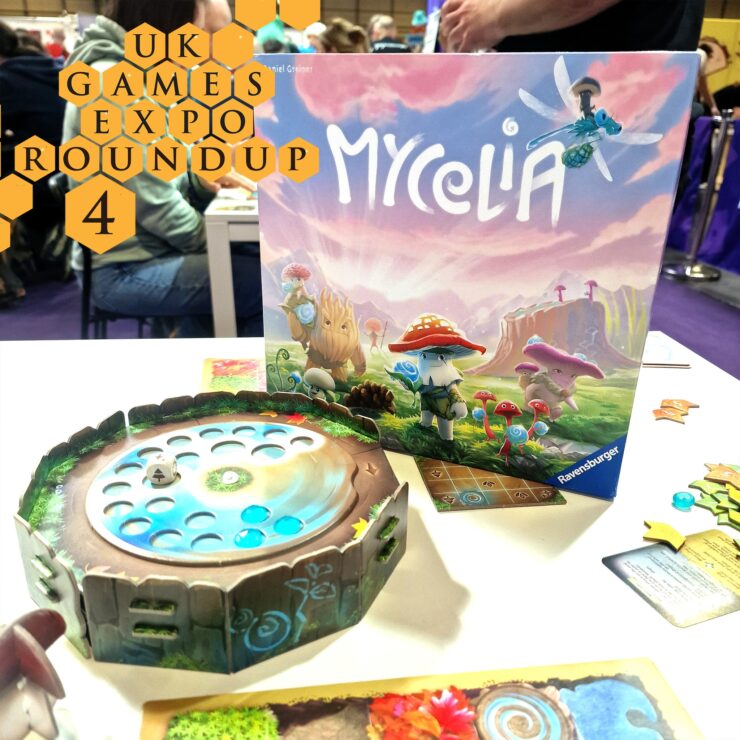 Image of the board game Mycelia displayed at the UK Games Expo, featuring the game box and a colorful game board with tokens. The scene captures a lively gaming environment with attendees in the background.