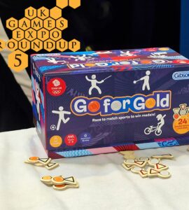 Go for Gold board game by Gibsons displayed at UK Games Expo, featuring colorful box art and sports-themed medal tokens. Suitable for ages 5 and up, designed for 2 to 8 players with a quick game time of 10 minutes.