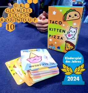 Colorful game box of "Taco Cat Goat Cheese Pizza" displayed at the UK Games Expo 2024, featuring playful illustrations of food characters. Stacked cards include "Ice Cream" design, emphasizing the game's fun and engaging nature. Awarded "Kinderspiel des Jahres 2024," highlighting its popularity among family-friendly games.