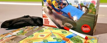 Box of the board game "Turbo Kidz" featuring colorful artwork of racing cars, placed next to a game map with rivers and landscapes, alongside a black item, promoting the Summer Marathon 2024 event.
