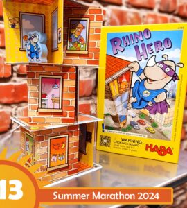 Colorful display of the "Rhino Hero" card game by HABA, featuring a stacked tower of cardboard rooms with playful illustrations, set against a brick background. The image promotes the Summer Marathon 2024 event, showcasing the game's vibrant box and character figures.