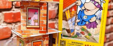 Colorful display of the "Rhino Hero" card game by HABA, featuring a stacked tower of cardboard rooms with playful illustrations, set against a brick background. The image promotes the Summer Marathon 2024 event, showcasing the game's vibrant box and character figures.