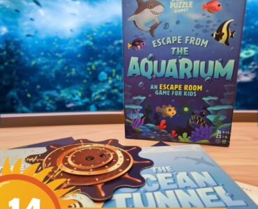 Colorful game box for "Escape from the Aquarium," an escape room game designed for kids aged 8-12, featuring underwater themes and playful graphics, displayed alongside game components on a table with an aquarium backdrop.