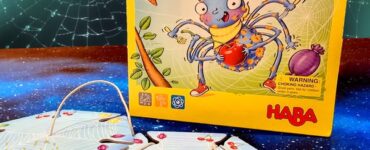 Colorful box of the game "Web Weavers" by HABA featuring a cartoon spider, with game pieces laid out on a starry background. Ideal for family fun and strategy gameplay, promoting cognitive skills in children.
