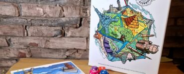 Colorful board game "Roll to the Top" displayed on a wooden table, featuring vibrant artwork and game components including dice and a score sheet, with a brick wall in the background. Ideal for family game nights and gatherings.