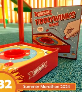 Colorful Tiddlywinks game by Super Retro Games, featuring a circular scoring board and a box design, suitable for up to four players. The image highlights the game setup on a green carpet, indicating its playful and engaging nature for family gatherings or game nights.