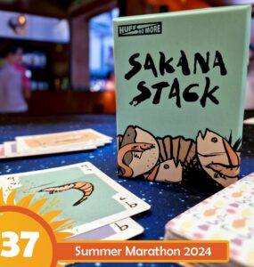 Sakana Stack card game box displayed on a table with playing cards featuring shrimp illustrations, set against a colorful background; Summer Marathon 2024 event highlighted in the corner.