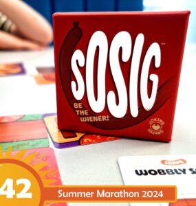 Red box of the game "sOSIG" featuring the tagline "Be the Wiener!" on a table with colorful game cards, hinting at a fun and interactive gaming experience for the Summer Marathon 2024.