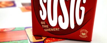 Red box of the game "sOSIG" featuring the tagline "Be the Wiener!" on a table with colorful game cards, hinting at a fun and interactive gaming experience for the Summer Marathon 2024.