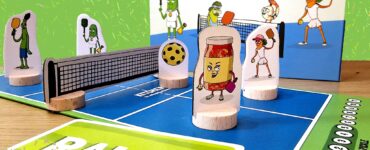 Colorful board game setup for "HotShot Pickleball," featuring playful character pieces, a net, and a game card labeled "RALLY," set against a vibrant background for the Summer Marathon 2024.