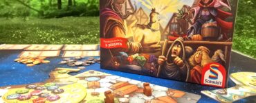 Image of the board game "The Quacks of Quedlinburg: The Duel" by Wolfgang Warsch, featuring vibrant artwork on the box and a game setup for two players. The scene includes game pieces and a colorful game board, set against a natural green background, with a label indicating "55 Summer Marathon 2024."