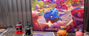 Colorful board game setup featuring "Robot Quest Arena," with various robot miniatures and game cards displayed on a table. The game box showcases vibrant artwork of robots in an arena setting, highlighting its playful theme. The image includes a banner for "Summer Marathon 2024" with the number 66.