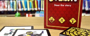 Board game "Steery" displayed with character cards, including a ninja, on a wooden table in front of a library backdrop. The game is suitable for 3-8 players, takes approximately 30 minutes to play, and is recommended for ages 10 and up.