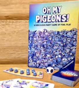 Board game "Oh My Pigeons!" by Ravensburger featuring colorful artwork, game cards, dice, and player pieces, set against a wooden background. Ideal for family game nights and parties.