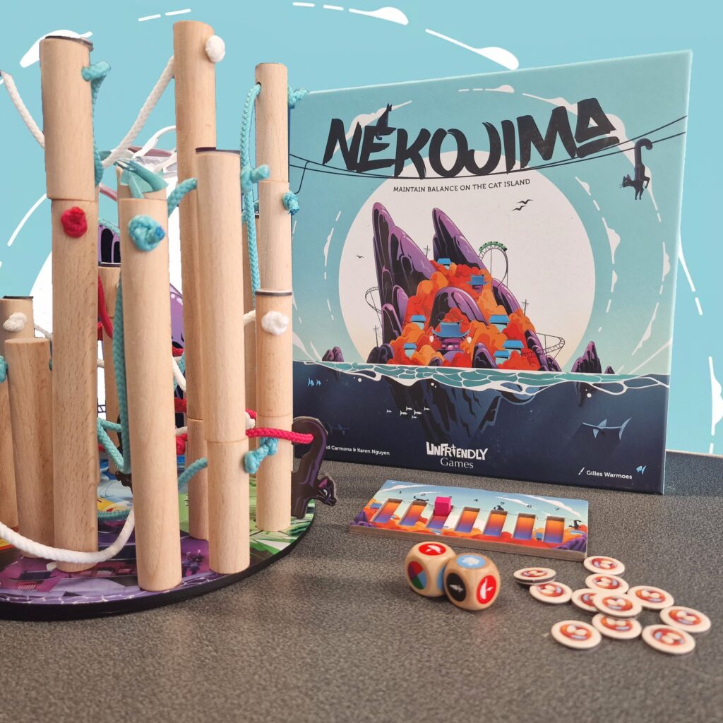 Nekojima board game setup featuring colorful wooden poles, ropes, and game components on a table, with the game box displaying vibrant artwork. Ideal for family fun and strategy play.