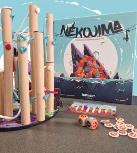 Nekojima board game setup featuring colorful wooden poles, ropes, and game components on a table, with the game box displaying vibrant artwork. Ideal for family fun and strategy play.