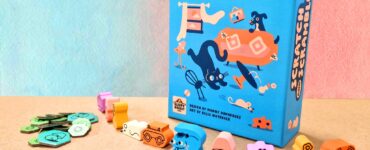 Colorful board game "Scratch and Scramble" displayed with its box and various playful tokens and pieces on a textured surface. The game features whimsical illustrations of animals and objects, making it visually appealing for family game nights.