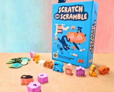 Colorful board game "Scratch and Scramble" displayed with its box and various playful tokens and pieces on a textured surface. The game features whimsical illustrations of animals and objects, making it visually appealing for family game nights.