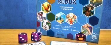 Board game "Rolling Realms: Redux" displayed with game components including dice and player sheets. The game is designed for 1-6 players, ages 14 and up, and features 12 new realms with a playtime of approximately 30 minutes.