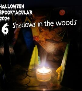Halloween Spooktacular 2024 promotional image featuring the title "Shadows in the Woods." The scene includes colorful wooden figures and a lit candle, creating an eerie ambiance suitable for Halloween festivities.