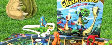 Colorful Gigantosaurus board game setup featuring a dinosaur-themed game board, character pieces, and the game box, all displayed on green grass. Perfect for family game nights and children's entertainment.
