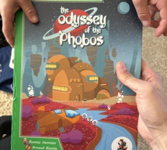 Child holding "The Odyssey of the Phobos" book from the "My First Adventure" series, featuring vibrant space-themed illustrations and engaging storyline. Ideal for young readers seeking interactive storytelling experiences.