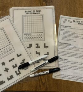 Printable game sheets for "Black It Out!" featuring player boards and game rules. The image showcases two player boards with grids and shapes, along with a rules sheet explaining gameplay and objectives. Markers are placed beside the sheets, ready for use.