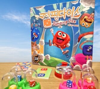 Colorful board game "Jumping Dice" featuring cartoon dice characters, game components including dice, cards, and a bell, set against a blue sky background.