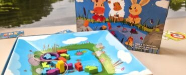 Colorful board game "Fishing Day" featuring a playful fishing scene, with vibrant wooden pieces and a scenic backdrop of a river and greenery. Ideal for family fun and skill development.
