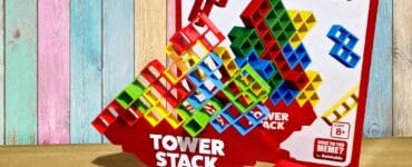 Colorful Tower Stack game set displayed on a wooden table, featuring a vibrant stacking tower, game cards, and the game box in the background. Ideal for family fun and skill development, suitable for ages 8 and up.