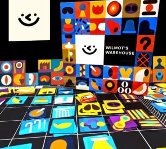 Colorful game pieces and the box of "Wilmot's Warehouse" are displayed against a black background. The box features a playful design with various shapes and a smiling face, while the scattered game pieces include vibrant icons in different colors and styles, showcasing the game's artistic theme.