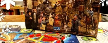 Alt text: Ticket to Ride: Legends of the West board game box displayed on a table with an illustrated game board featuring colorful train routes and player pieces. The scene is decorated with snowflake graphics, indicating a festive theme.