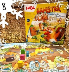 Colorful board game "Hamster Clan" by HABA displayed on a straw background, featuring game pieces and a vibrant game board, suitable for ages 4 and up.