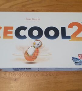 Ice Cool 2 board game box featuring colorful graphics and a penguin character, designed by Brian Gomez, displayed on a wooden table.