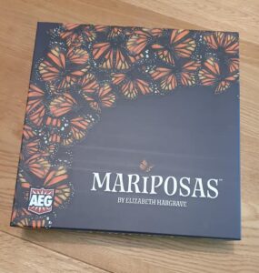 Game box for "Mariposas" by Elizabeth Hargrave, featuring a vibrant design of orange and black butterflies on a dark background, with the AEG logo in the corner.