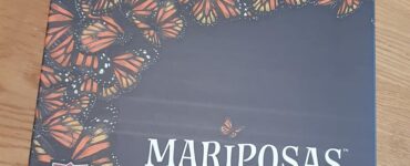 Game box for "Mariposas" by Elizabeth Hargrave, featuring a vibrant design of orange and black butterflies on a dark background, with the AEG logo in the corner.