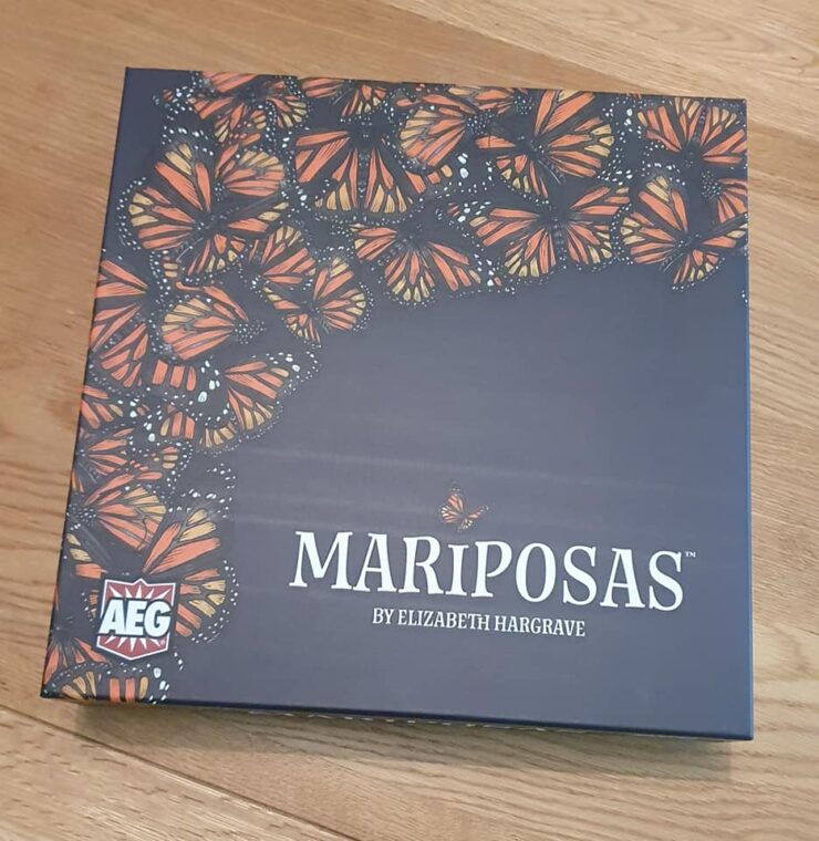 Game box for "Mariposas" by Elizabeth Hargrave, featuring a vibrant design of orange and black butterflies on a dark background, with the AEG logo in the corner.