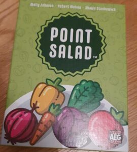 Board game "Point Salad" featuring colorful vegetable illustrations on the box cover, designed by Molly Johnson, Robert Melvin, and Shawn Stankiewich. The artwork includes various vegetables like carrots, peppers, and leafy greens, set against a green background.