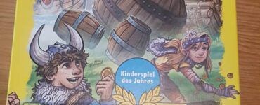 Colorful board game box for "Valley of the Vikings" by HABA, featuring Viking characters and barrels. The design highlights the game's theme of knocking over barrels while trying to stay dry. It includes a warning about choking hazards and mentions the game is suitable for ages 6 and up. Recognized as the Children's Game of the Year 2019.