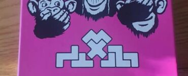 Colorful game box for "Team 3," featuring three cartoon monkeys with playful expressions, set against a bright pink background. The design includes the game's title and logos of the creators, Matt Fantastic, Alex Cutler, and Reinis Pētersons. Perfect for board game enthusiasts.