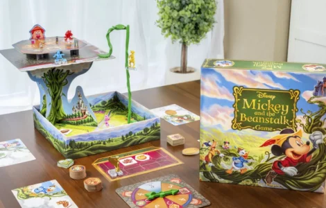 Colorful Disney board game "Mickey and the Beanstalk" displayed on a wooden table, featuring a 3D game board, character pieces, and game cards, set in a bright indoor environment with a plant in the background.