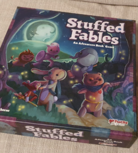 Colorful box cover of the board game "Stuffed Fables," featuring whimsical stuffed animal characters on an adventure under a moonlit sky, designed by Jerry Hawthorne and published by Plaid Hat Games.