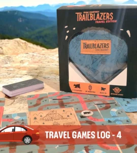 Trailblazers Travel Edition game box displayed on a rocky surface, surrounded by game cards featuring outdoor illustrations, suitable for 1-4 players and ages 8 and up. Ideal for road trips and family fun, emphasizing engagement with nature.
