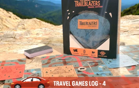 Trailblazers Travel Edition game box displayed on a rocky surface, surrounded by game cards featuring outdoor illustrations, suitable for 1-4 players and ages 8 and up. Ideal for road trips and family fun, emphasizing engagement with nature.