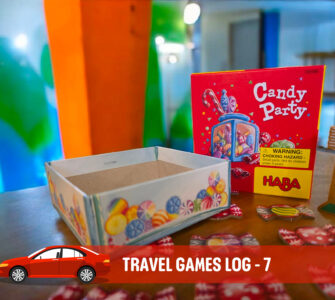 Colorful Candy Party game box by HABA displayed on a table, featuring candy tokens scattered around, with a blank game container nearby. The background showcases vibrant painted walls, enhancing the playful atmosphere of family travel games.