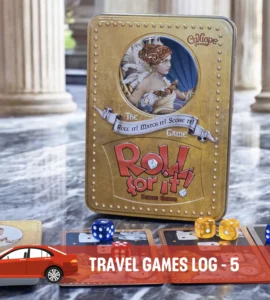 Alt text: A close-up of the board game "Roll for It!" Deluxe Edition displayed on a marble surface, featuring its distinctive gold tin box and colorful dice. Accompanying cards are spread out, showcasing artwork and game components, in a stylish setting with classical pillars in the background.