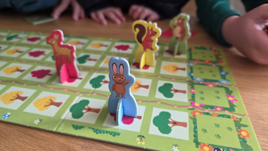Colorful game pieces featuring animals on a vibrant board, with children’s hands in the background, showcasing a fun and engaging family board game setup.